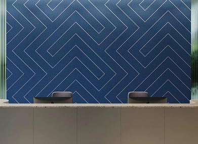 Reception desk against a blue wall, featuring chairs and acoustic panels for sound absorption.
